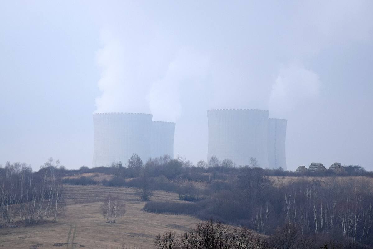 Čtyři chladicí věže jaderné elektrárny Temelín v mlze nad zimní krajinou s holými stromy