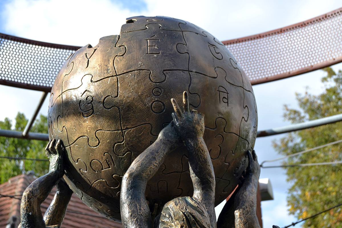 Bronzový pomník Wikipedie ve Słubicích, koule složená z dílků skládačky nesená rukama