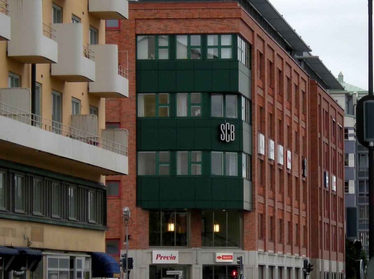 Cihlová budova s tmavě zeleným arkýřem a nápisem SCB na rohu ulice v Örebru