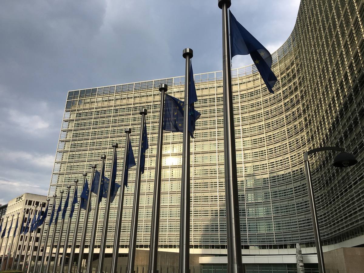 Prosklená budova Berlaymont v Bruselu s řadou vlajek Evropské unie před vchodem