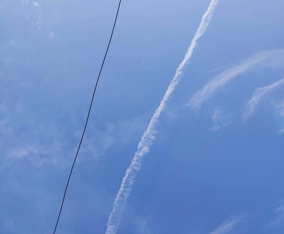 Kondenzační stopa letadla na modré obloze