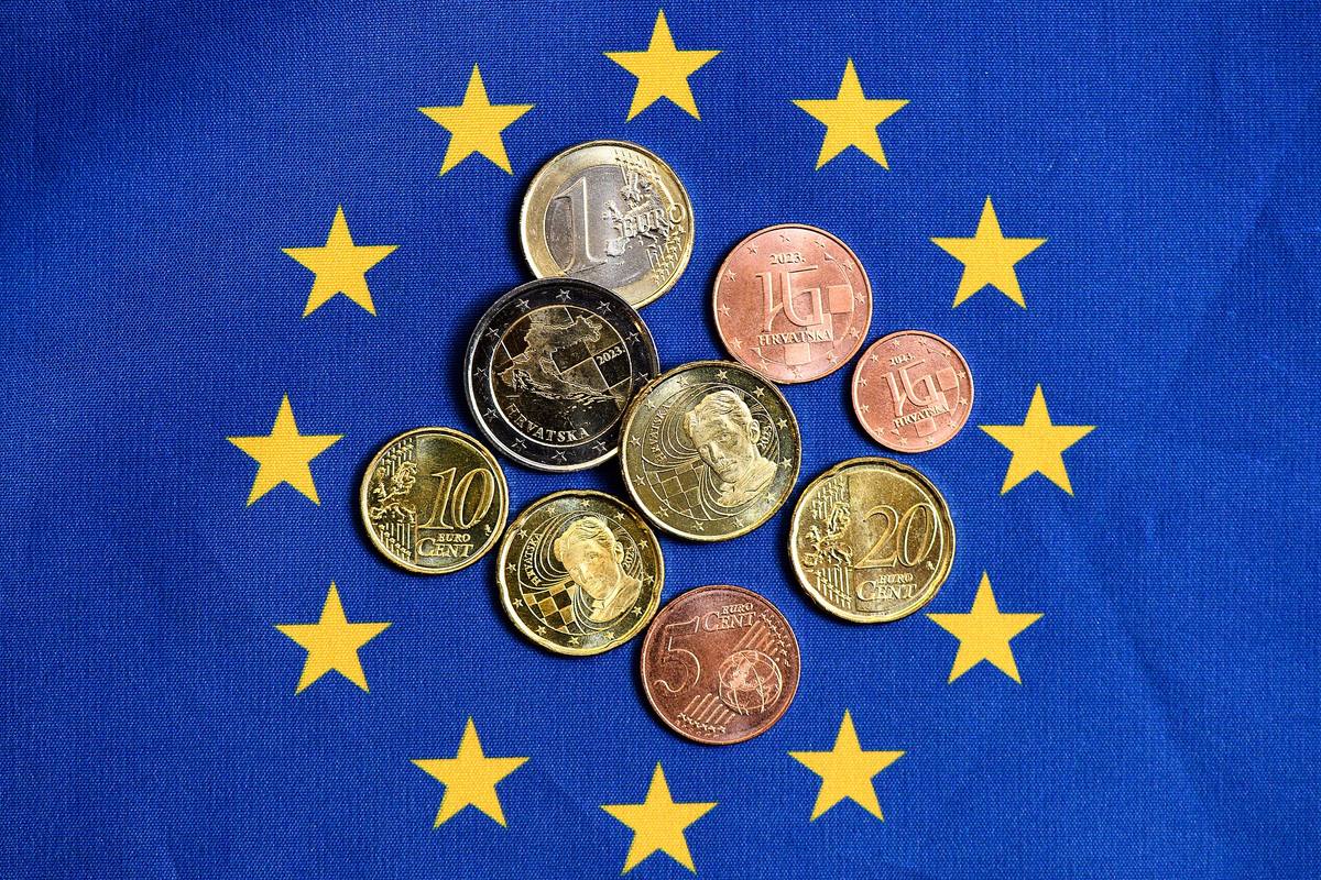 Chorvatské eurové mince rozložené na vlajce Evropské unie, na dvoueurové je mapa Chorvatska a letopočet 2023