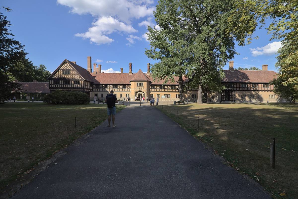Zámek Cecilienhof v Postupimi, rozlehlá cihlová stavba s hrázděnými štíty a trávníkem před průčelím