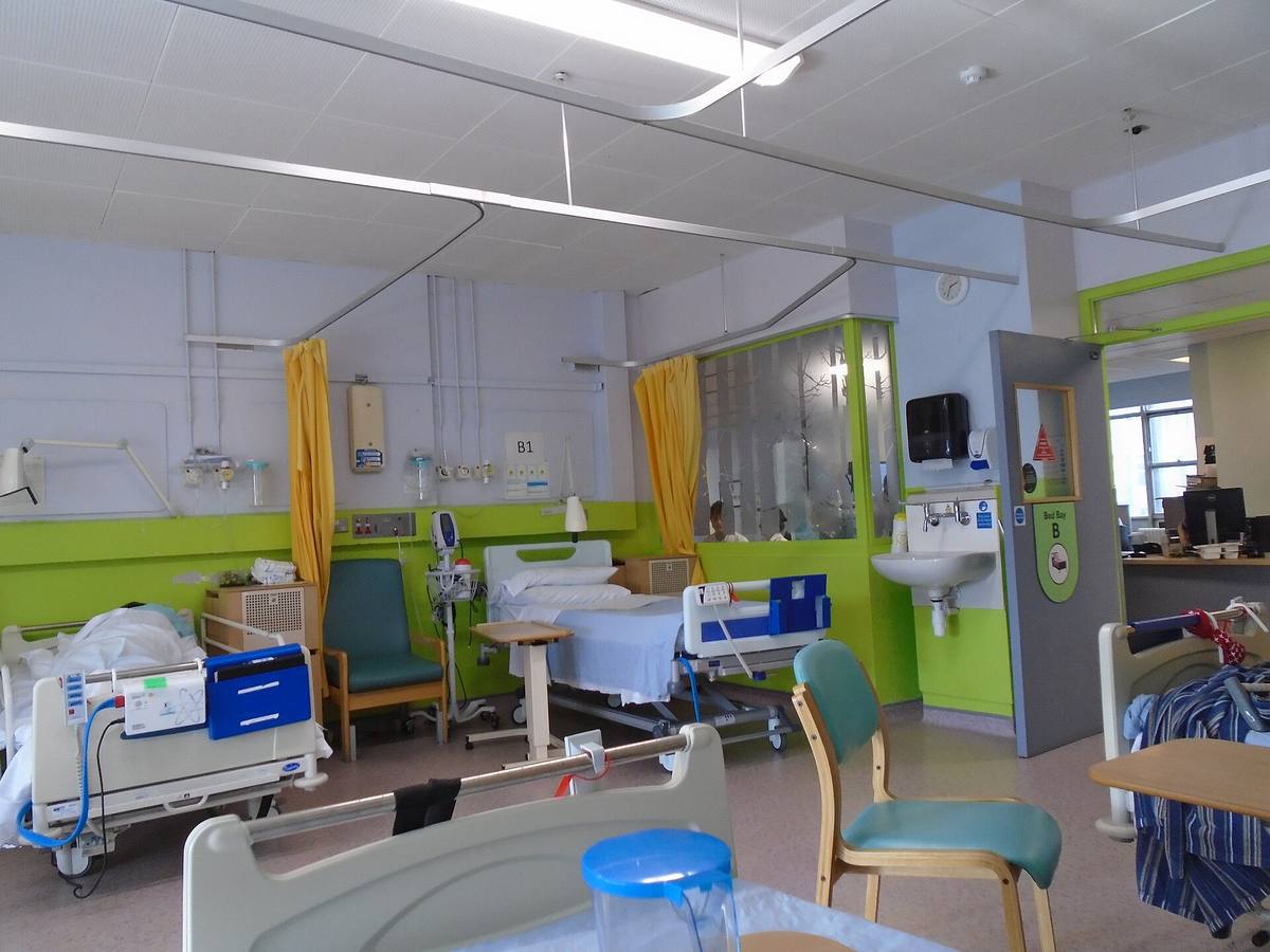 Nemocniční pokoj s prázdnými lůžky, zataženými zástěnami a monitorovací technikou