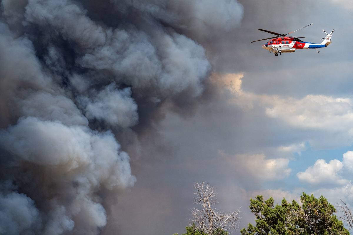 Hasicí vrtulník Sikorsky S-70 Firehawk v letu nad kouřem z lesního požáru